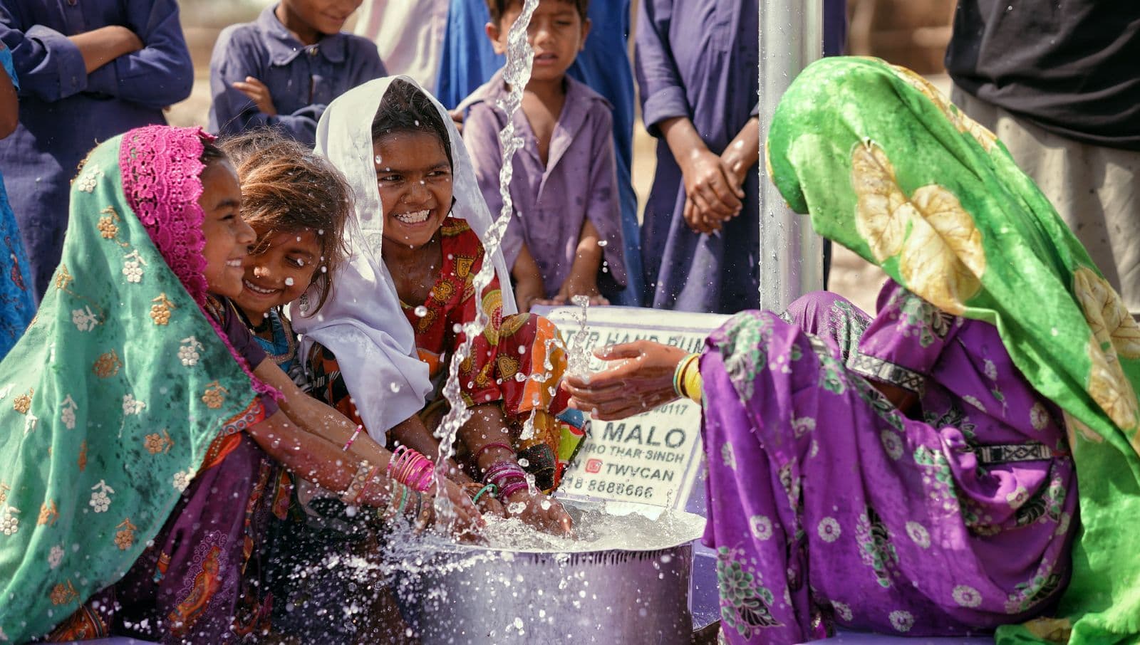 Children playing in water at a village hand pump.