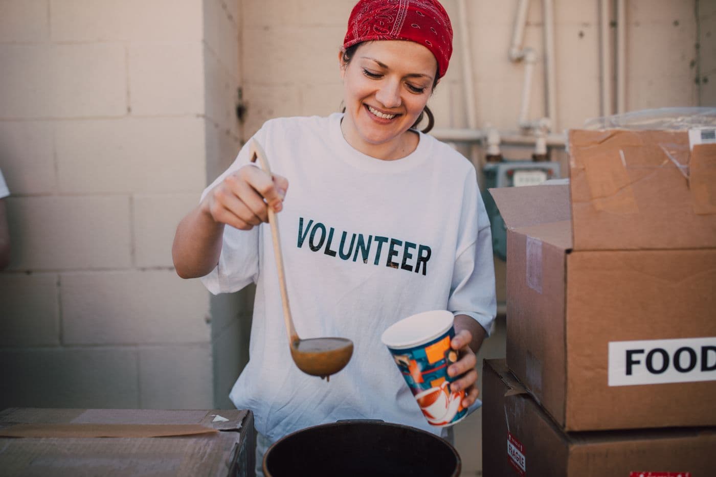 A volunteer serving hot food from a large pot.