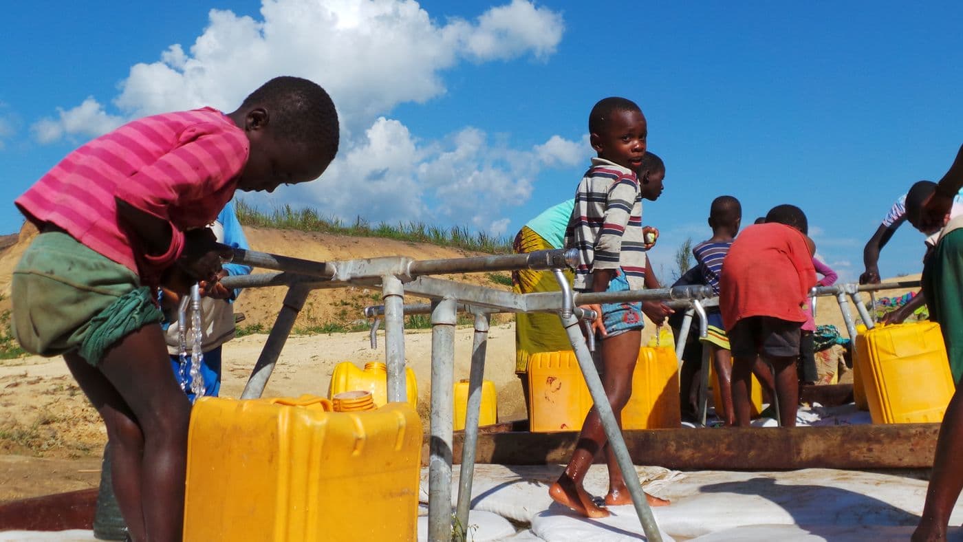 Children filling yellow jerrycans at a village water point.